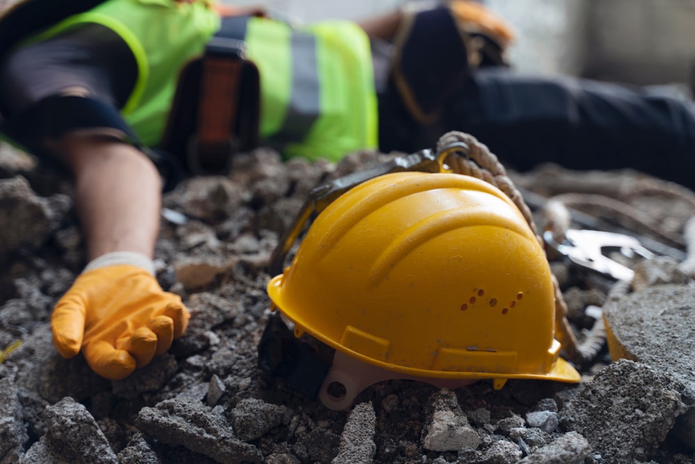 Construction Worker Unconscious Laying On The Ground With His Helmet Next To Him 