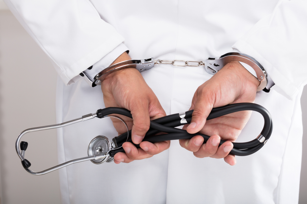 Photo of Doctor in Handcuffs Holding Stethoscope